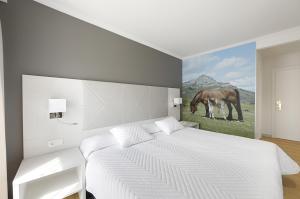 a bedroom with a white bed with a painting of a horse at Hotel Loiola in Azpeitia