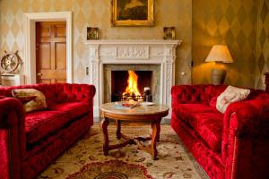 a living room with two red couches and a fireplace at Dunbrody Country House Hotel in Arthurstown