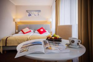 a hotel room with a bed and a table with a book at HOTEL*** NAT Bukowina Tatrzańska in Bukowina Tatrzańska