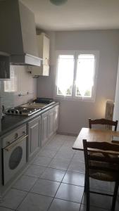 eine Küche mit einem Herd, einem Tisch und Fenstern in der Unterkunft Appartement PAP2S in Millau
