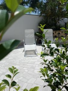 Duas cadeiras brancas estão sentadas num pátio em Il Vicoletto em Casamassella