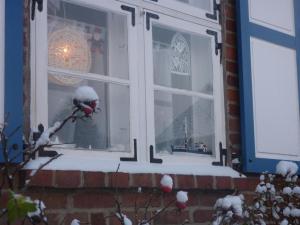 a window of a house with snow on it at Alte Kate mit Bau-& Zirkuswagen im Gartenidyll in Kasnevitz