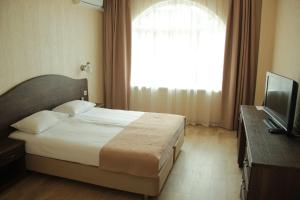um quarto com uma cama, uma televisão e uma janela em Agama Hotel em Yakornaya Shchel