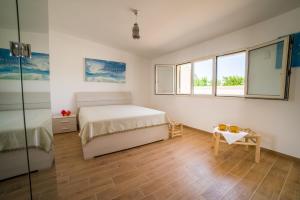 a bedroom with a bed and a table and windows at I Ruscioli in Torre Chianca +39 photos