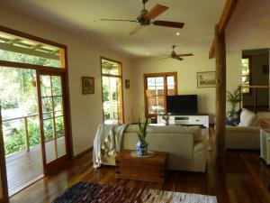 een woonkamer met een bank en een plafondventilator bij Magnolia Cottage in Cooroy
