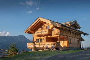a large wooden house with chairs in front of it at Prenner Alm in Haus im Ennstal