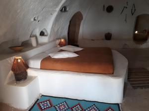 een slaapkamer met een wit bed met een licht erop bij Au Trait d'Union Tijma Matmata in Matmata