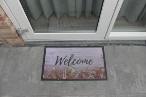 a welcome sign on the sidewalk in front of a door at Zon Zee Zoutelande in Zoutelande