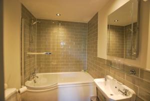 ein Badezimmer mit einer Badewanne, einem Waschbecken und einem Spiegel in der Unterkunft Ye Olde Fighting Cocks in Arnside