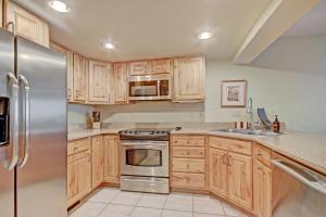 a kitchen with wooden cabinets and a stainless steel refrigerator at Cm244 Copper Mtn Inn Condo in Copper Mountain