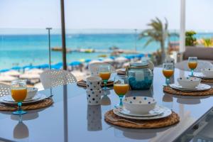 a table with glasses of orange juice and coffee on the beach at Sunprime Protaras Beach - Adults Only in Protaras