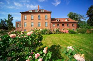 a large brick building with a yard with roses at Gutshaus Gottin in Warnkenhagen
