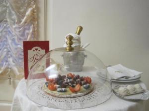 マリーナ・ディ・マッサにあるHotel Matildeの皿に盛った果物入りのガラスドームのケーキ