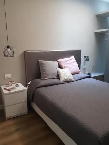 łóżko z różowymi i szarymi poduszkami i stolikiem. w obiekcie La Baita Del Re Resort w mieście Ottaviano