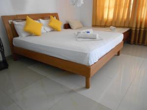 ein Schlafzimmer mit einem Bett mit gelben und weißen Kissen in der Unterkunft Shanith Guesthouse Negombo in Negombo