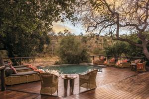 uma piscina num deque com cadeiras e uma mesa em Tuningi Safari Lodge em Madikwe Game Reserve