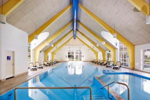 einen Pool mit Stühlen in einem Gebäude in der Unterkunft H+ Hotel Ferienpark Usedom in Ostseebad Koserow