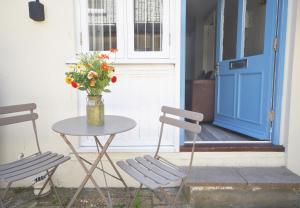 een tafel en twee stoelen en een tafel met een vaas met bloemen bij Trinity Mews in Torquay