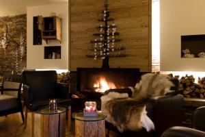 a living room with a fireplace and a chair at Hotel Vedig in Santa Caterina Valfurva