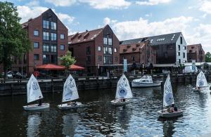 a group of small sailboats in a river with buildings at Mieterlux 22 in Klaipėda
