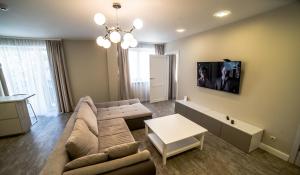uma sala de estar com um sofá e uma televisão na parede em Mieterlux 22 em Klaipeda