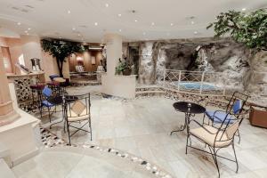 a lobby with a stone wall with tables and chairs at Sporthotel Kirchler in Tux