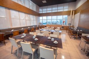 comedor con mesas y sillas y ventanas grandes en Iguatemi Business & Flat by Avectur, en Salvador