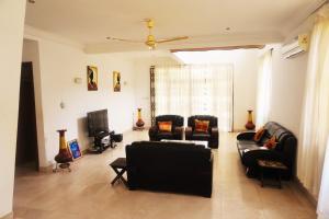 a living room with black couches and a tv at Sandpark Place, West Hills in Accra