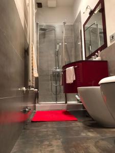 La salle de bains est pourvue d'une douche et d'un tapis rouge. dans l'établissement Nonna Anna, à Sienne