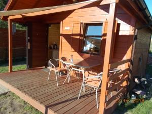 a cabin with a table and chairs on a deck at Niewygodny Domek z własnym podwórkiem in Wisełka