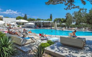 a group of people sitting in lounge chairs by a pool at Pharos Hvar Hotel in Hvar