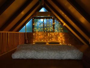 a bedroom with a bed in a attic with lights at 猫とピアノと星空のリゾートブティックコテージ -Starry Forest Cottage Okinawa- in Onna