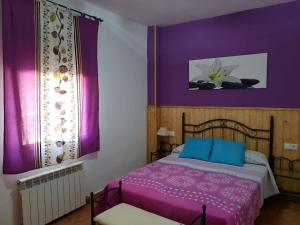 アロヨ・フリオにあるAlojamiento Alarconの紫の壁のベッドルーム1室、紫のベッドカバー付きのベッド1台が備わります。