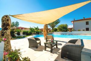 a patio with chairs and a table next to a pool at Case Vacanze Budoni Beach in Budoni