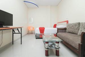 a room with a bed and a couch and a tv at RedDoorz Plus @ Jalan Pemuda Jakarta in Jakarta