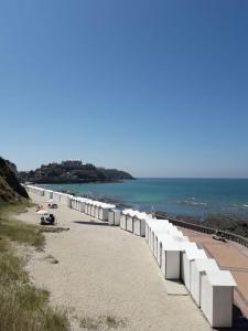 Une longue ligne de barrières blanches sur une plage dans l'établissement Granville Plage Plat Gousset, à Granville