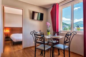 a dining room with a table and chairs and a window at Zenitude Hôtel-Résidences Les Jardins de Lourdes in Lourdes