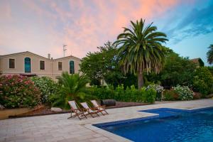 a house with a pool and two chairs and a palm tree at Mas Palou in Pla del Panadés