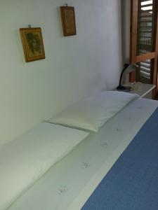 ドンナルカータにあるIl 7 e il 13の白いベッド1台、壁に2枚の写真が飾られたベッドルーム1室