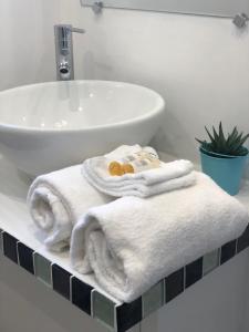 - une salle de bains avec des serviettes blanches sur un comptoir à côté d'un lavabo dans l'établissement Perla Di Macchia, à Bonifacio