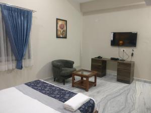 a room with a bed and a chair and a television at Misty Lake Guest House in Hyderabad