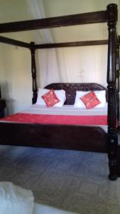 a bed with a wooden frame with red pillows on it at Platinum Hotels Mombasa in Shanzu