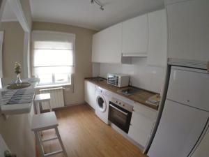 a kitchen with white cabinets and a stove top oven at La Posada de Granda in Cuenco