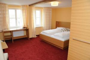 a bedroom with a bed and a desk and windows at Hotel Stiegenwirt in Schärding