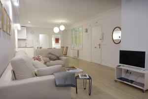 ein weißes Wohnzimmer mit einem Sofa und einem TV in der Unterkunft ARCH. in San Sebastián