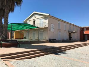 a building with a green canopy next to a palm tree at Albergue De Puntas De Calnegre in Calnegre