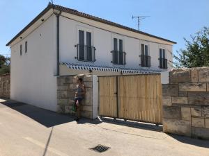a woman standing in front of a house with a garage at Boho House in Pakoštane