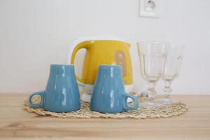 two blue cups sitting on a table with glasses at Boho House in Pakoštane