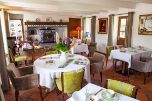 a dining room with tables and chairs and a fireplace at Le Colombier in Wissant