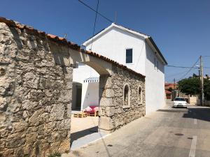a white building with a stone wall next to a street at Boho House in Pakoštane